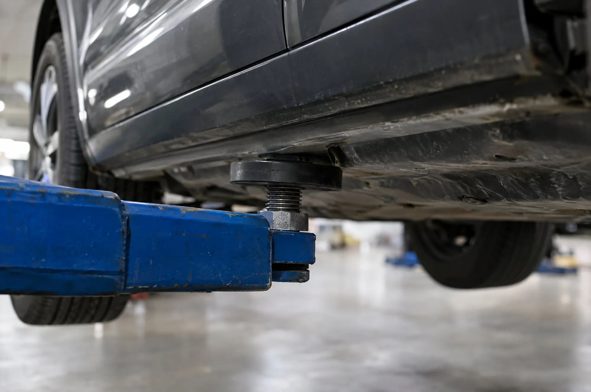 Lift arm pad set under the frame of a raised SUV in the service bay
