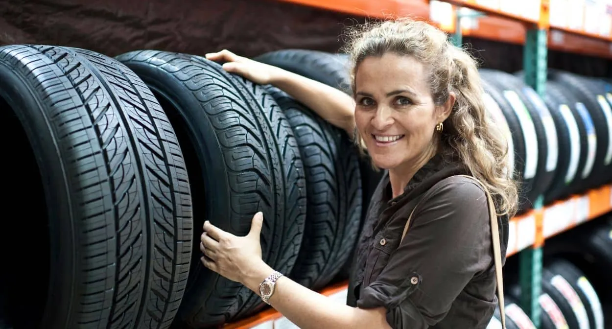 Smiling customer choosing a tire from a rack of new tires