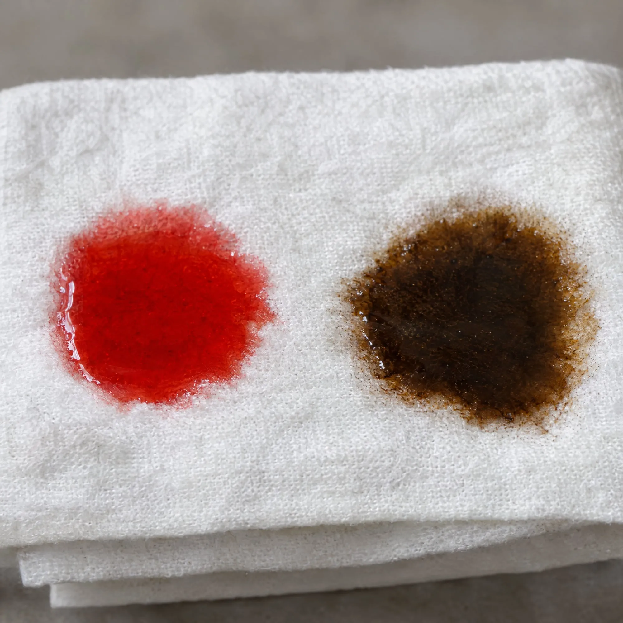 Bright red fresh transmission fluid next to dark brown old fluid on a white shop towel